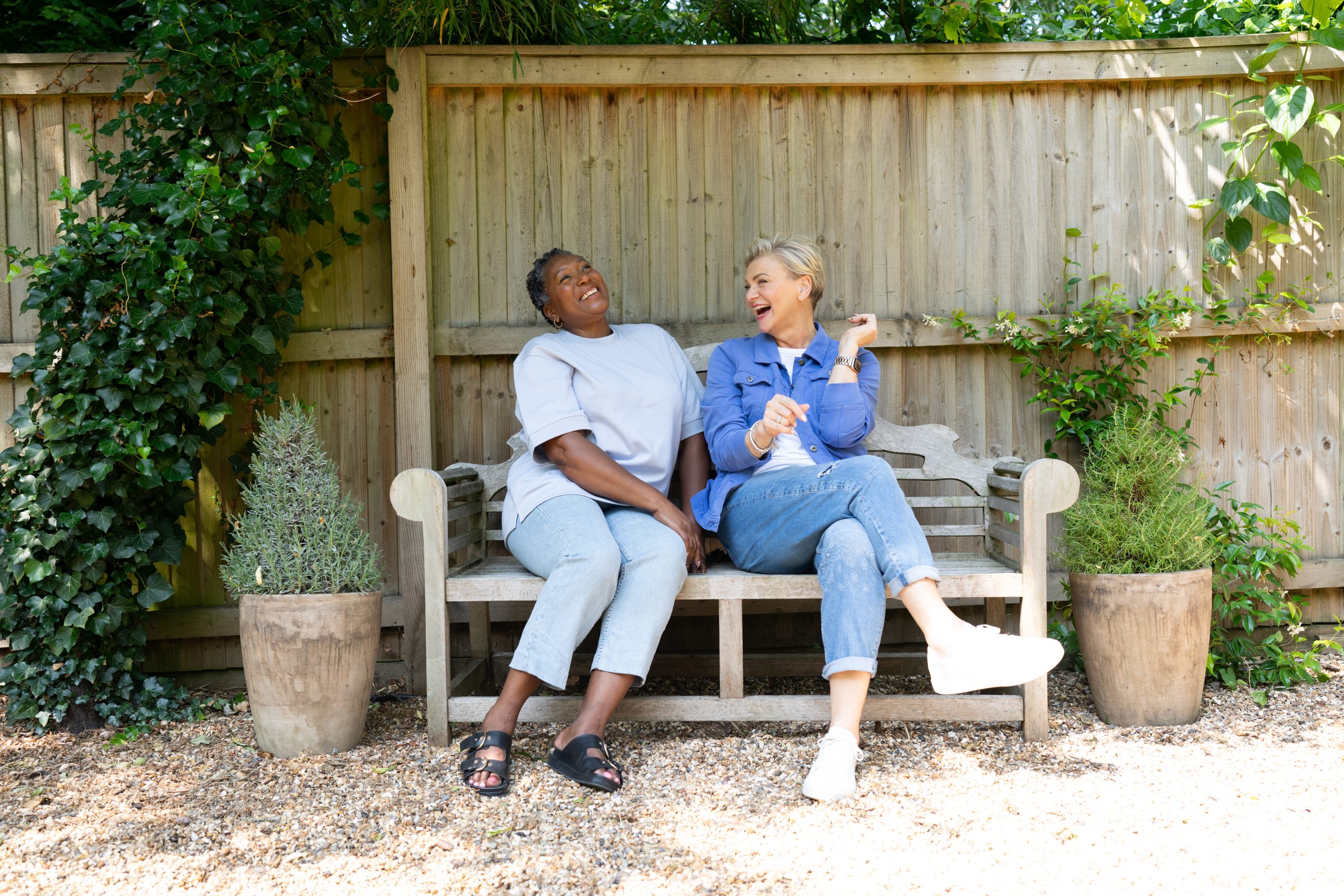 2 women sat on a bench laughing.
