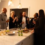 5 people laughing in kitchen celebrating