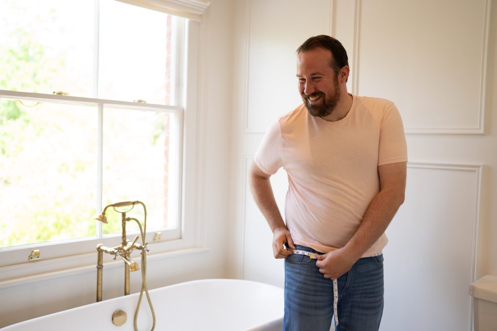 man measuring thigh in bathroom