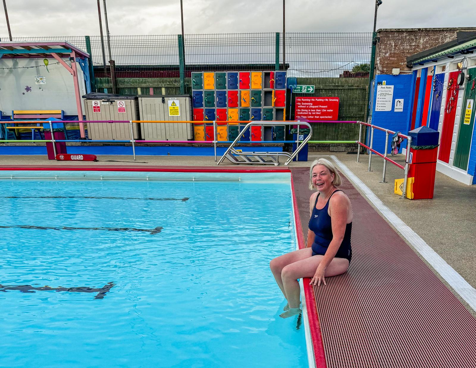 Emma sat with feet in outdoor swimming pool